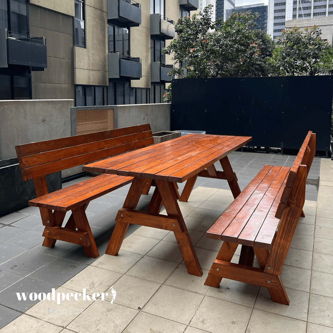 A rustic picnic table set with a robust wooden table and ergonomic benches with backrests, perfect for enjoying meals in your backyard.