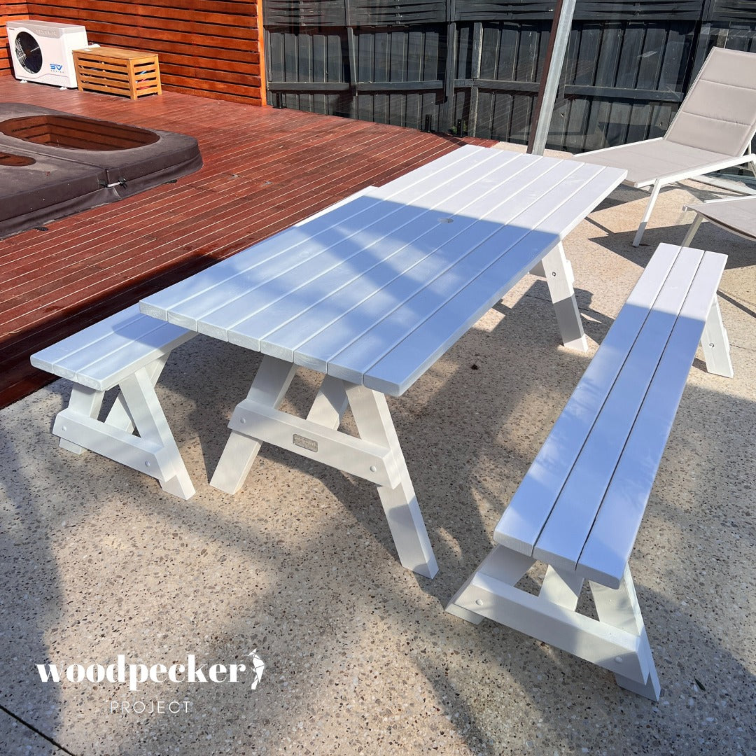 A contemporary picnic table set with a minimalist design, featuring a weather-resistant wooden surface and detachable benches for versatility